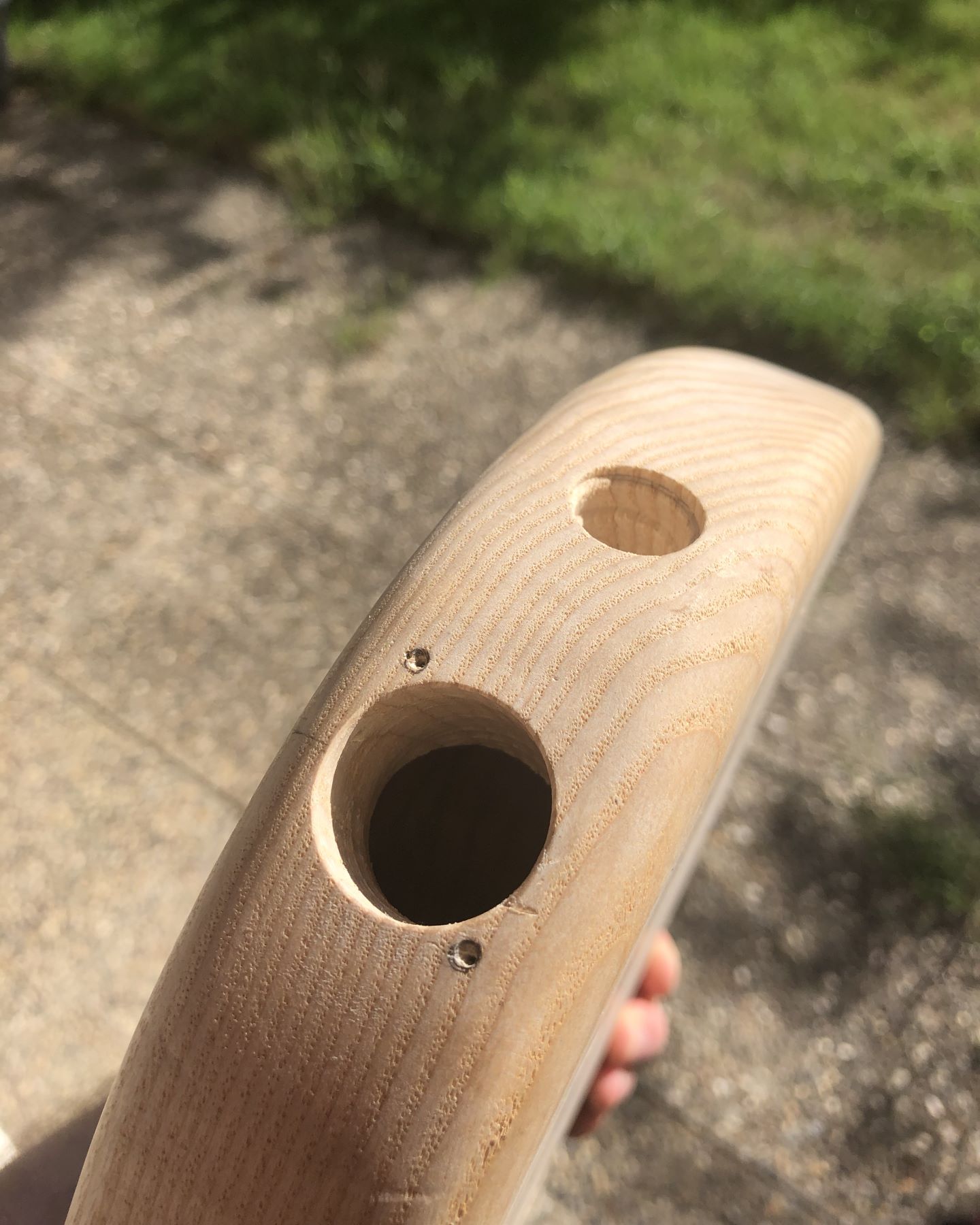 Side view photo of the bass guitar body with a large 24 mm hole centered on the side of the body with two much smaller holes less than 3 mm from the large hole. A smaller hole for a regular deep panel jack is visible as well.